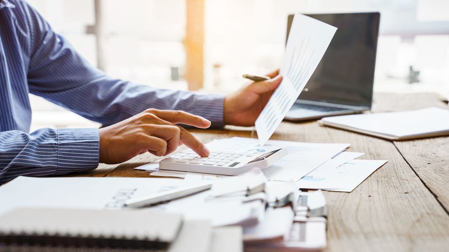 Man doing calculations with a calculator, holding paper and pen