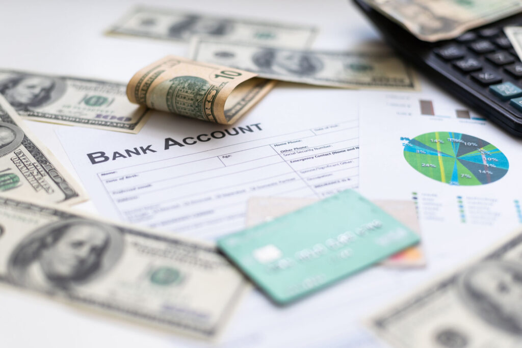Bank account ledger with money laying on top with credit card